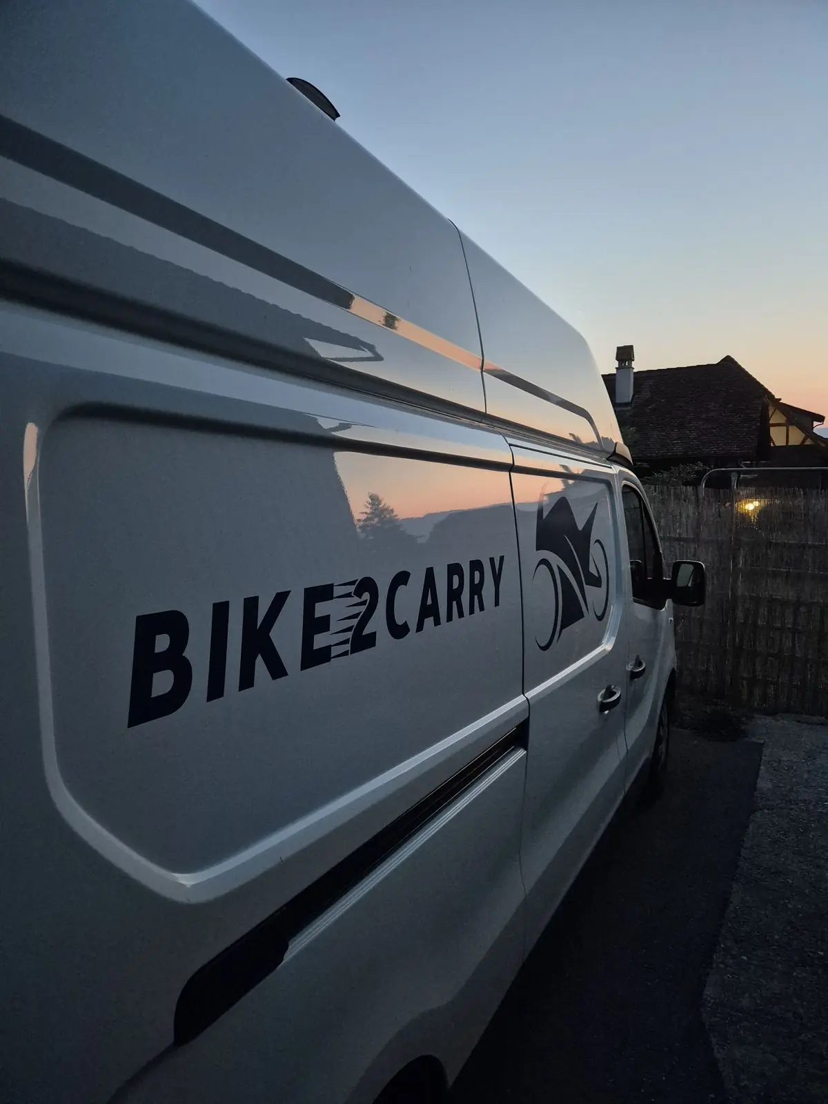 Bike2Carry-Schriftzug auf der Seitenwand des Transporters in der Abenddämmerung