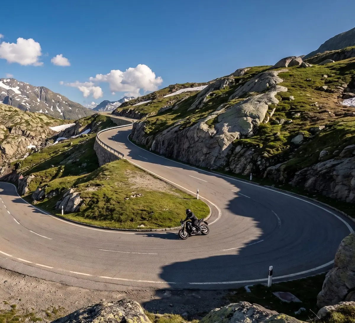 Motorradfahrer in einer Kehre auf einem Alpenpass im Sommer