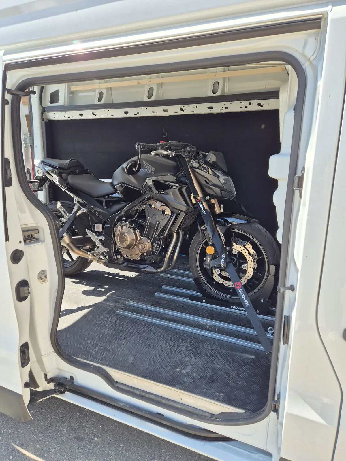 Motorrad steht festgezurrt im Laderaum, Blick durch die Schiebetür
