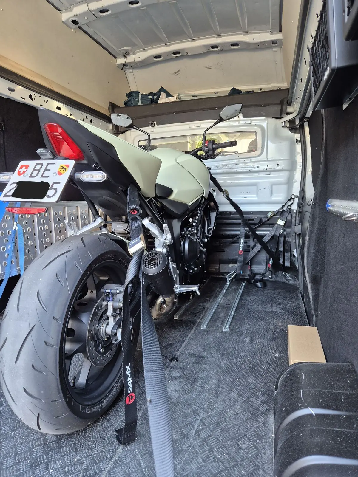 Motorrad mit Spanngurten im Laderaum fixiert, Blick von hinten